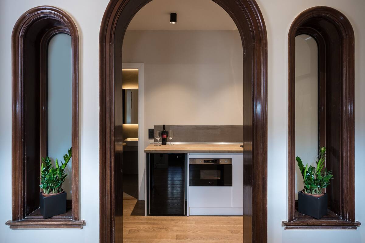 A hallway with wooden flooring and a kitchen area in the background.