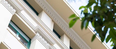 A building facade with multiple balconies and windows, featuring classical architectural elements.