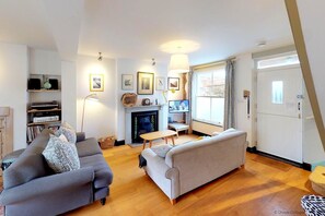 Una sala de estar moderna con chimenea, dos sofás, un televisor y una estantería.