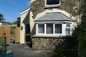 Escape to a charming cottage with a bay window and garden, perfect for a peaceful retreat.