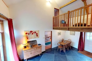 A cozy room with a dining area, a wooden staircase, and a view of the outdoors.