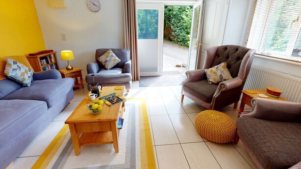 A living room with a sofa, armchair, coffee table, and a yellow rug.