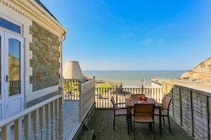 Enjoy the ocean view from this balcony with a table and chairs.
