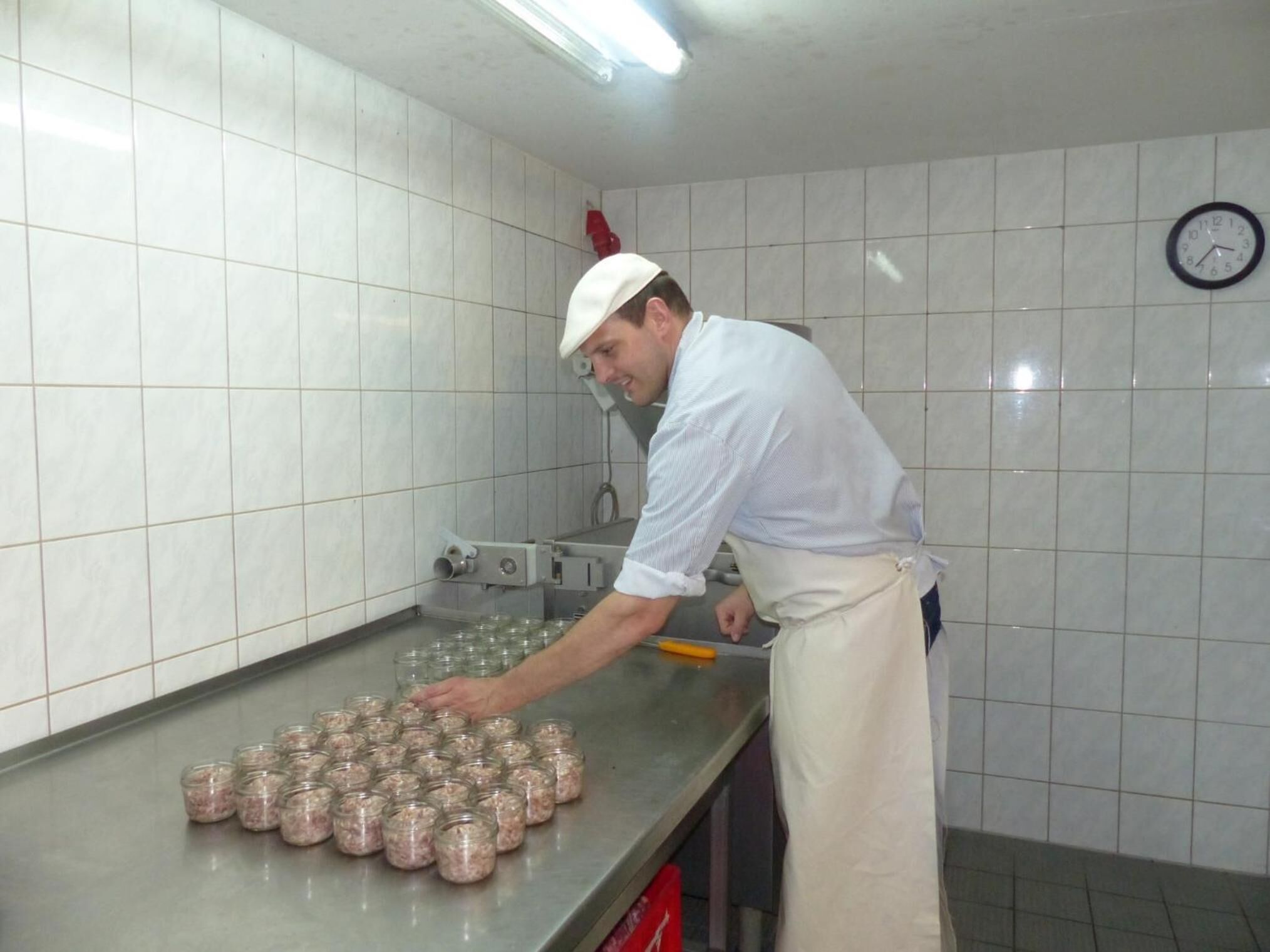 Una cocina con salpicadero de azulejos, encimeras de acero inoxidable y un reloj en la pared.