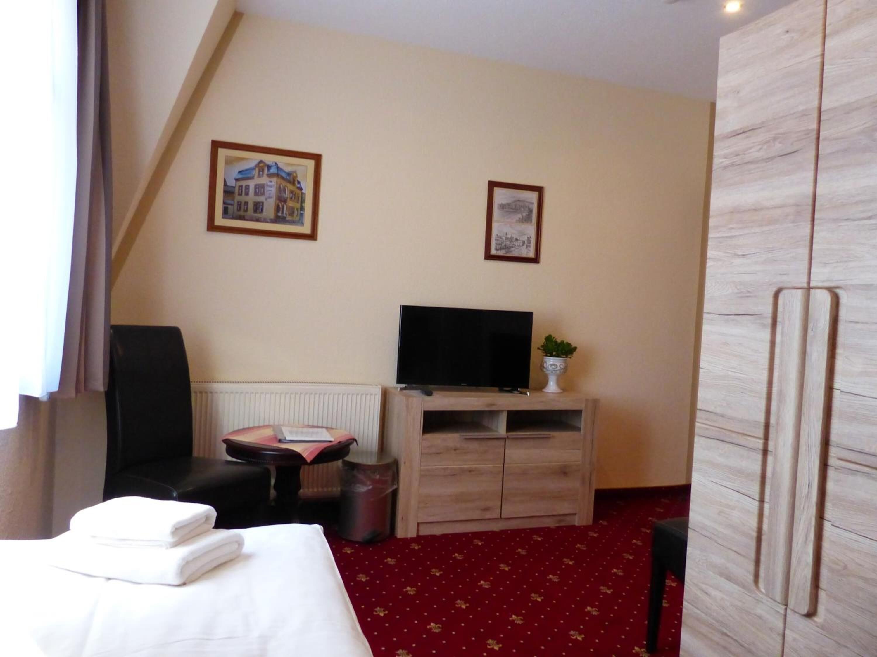 Una camera d'albergo con un letto, una scrivania, una sedia, una televisione e un tavolino.