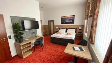 Una habitación de hotel con cama, escritorio, televisor, silla y mesa.