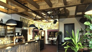 A bar area with wooden beams, a bar counter with bottles, and a mural on the wall. - Hotel Friedchen (Artern/Unstrut)