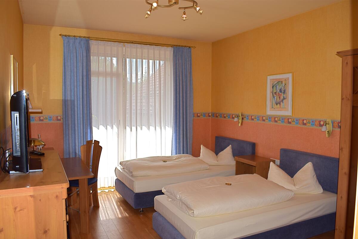 A hotel room with two beds, a desk, and a chair.