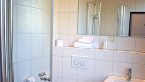Een moderne badkamer met toilet, wastafel en douchecabine met glazen wanden.