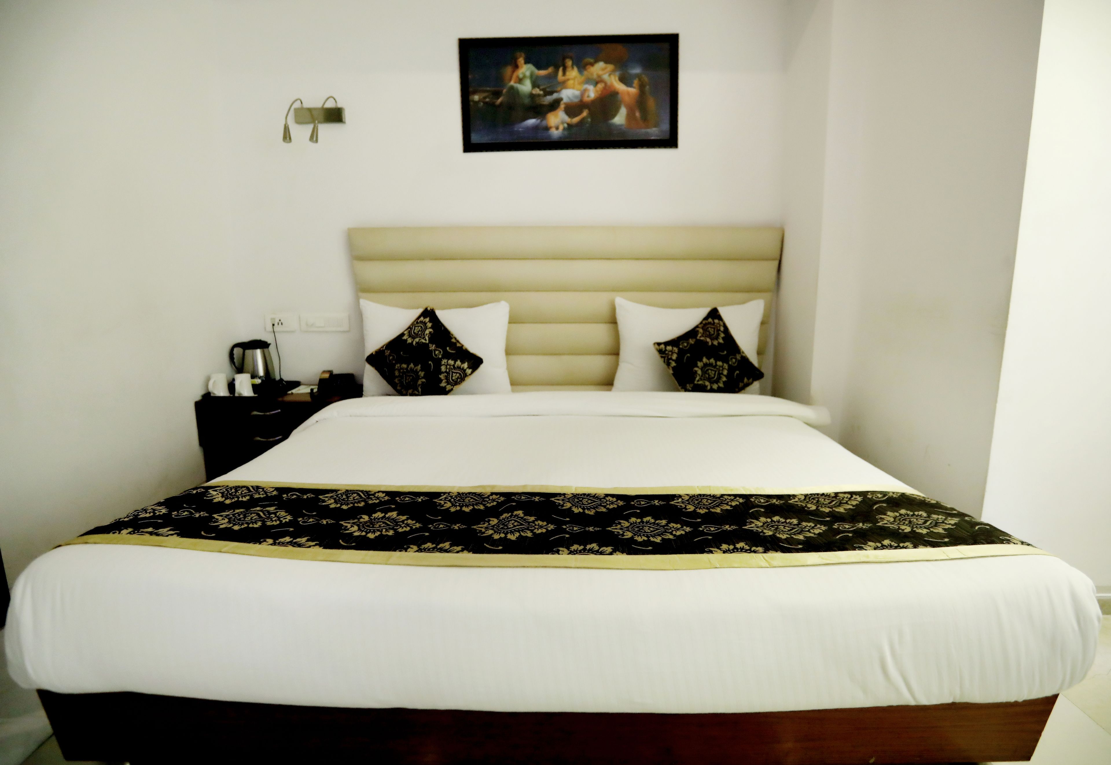 Een net opgemaakt bed met een geborduurd sprei en twee sierkussens.