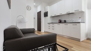 A modern kitchen with white cabinets, a black sofa, and a coffee machine. - Italianway   - Segrino 6 (Milan)