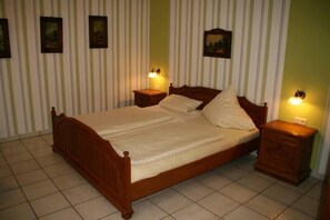 A wooden bed with two nightstands, a striped wallpaper background, and framed pictures on the wall. - Hotel Restaurant Schütz (Trier)