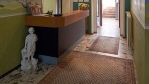 A reception area with a 'RECEPTION' sign, a reception desk, a statue, and a hallway leading to another room. - Hotel Restaurant Schütz (Trier)