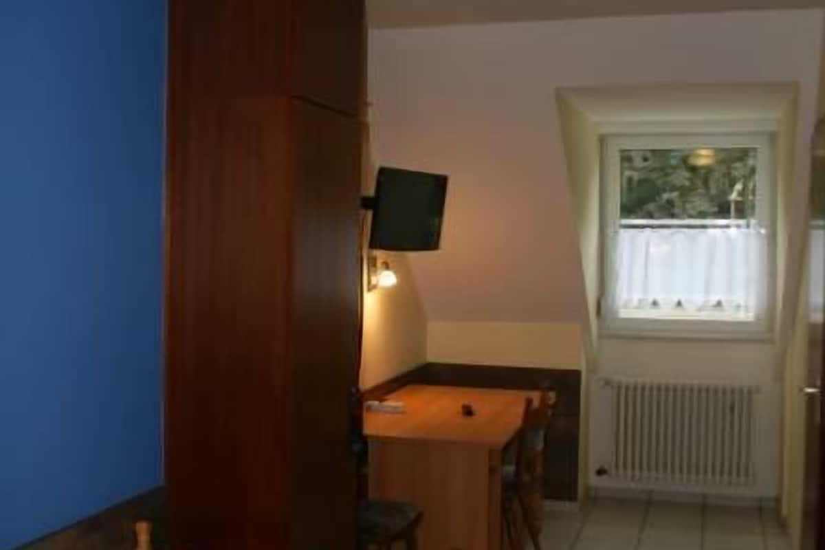 A small room with a bed, a desk, and a window.
