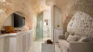 A cozy living room with a stone archway, a flat-screen TV, a coffee table, and a sofa. - San Michele Suite (Polignano a Mare)