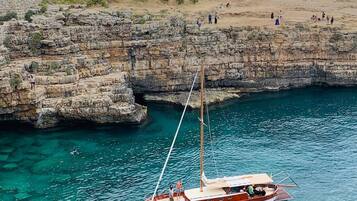 Un barco fondeado cerca de acantilados rocosos con agua turquesa cristalina.