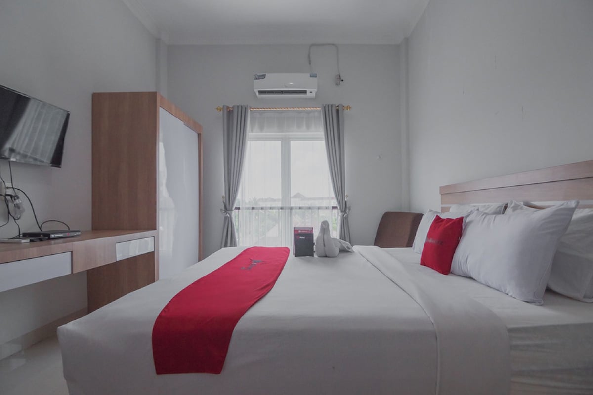 Ein Hotelzimmer mit Bett, Schreibtisch, Fernseher und Klimaanlage.