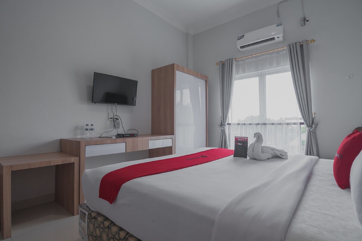 Ein Hotelzimmer mit Bett, Schreibtisch, Fernseher und Klimaanlage.