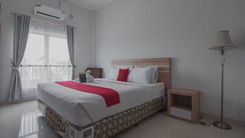 A hotel room with a large bed, a bedside table, a lamp, and a window with curtains.