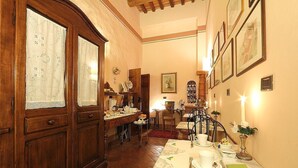 A dining area with a wooden table set for a meal, a chandelier, and framed artwork on the walls. - Villa Il Colle (Bagno a Ripoli)