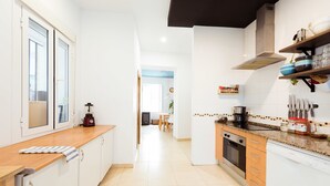A modern kitchen with white cabinets, a wooden countertop, and a built-in oven. - La Casa Morada - Hostel (Cádiz)