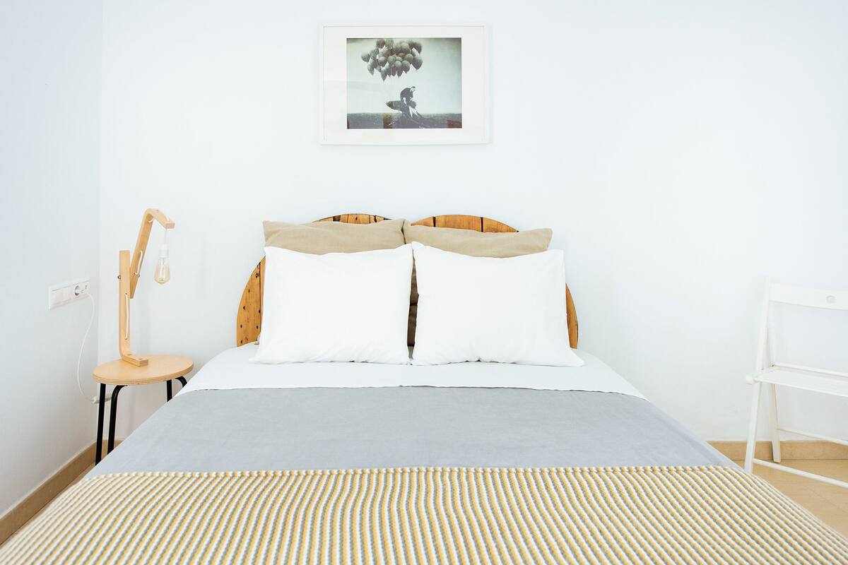 A neatly made bed with a striped bedspread, a wooden headboard, and a bedside table with a lamp.