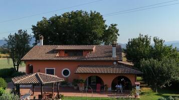A two-story house with a tiled roof, a patio with outdoor furniture, and a garden in front.