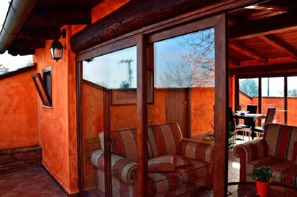 A cozy interior with a wooden ceiling, large sliding glass doors, and striped upholstered chairs.