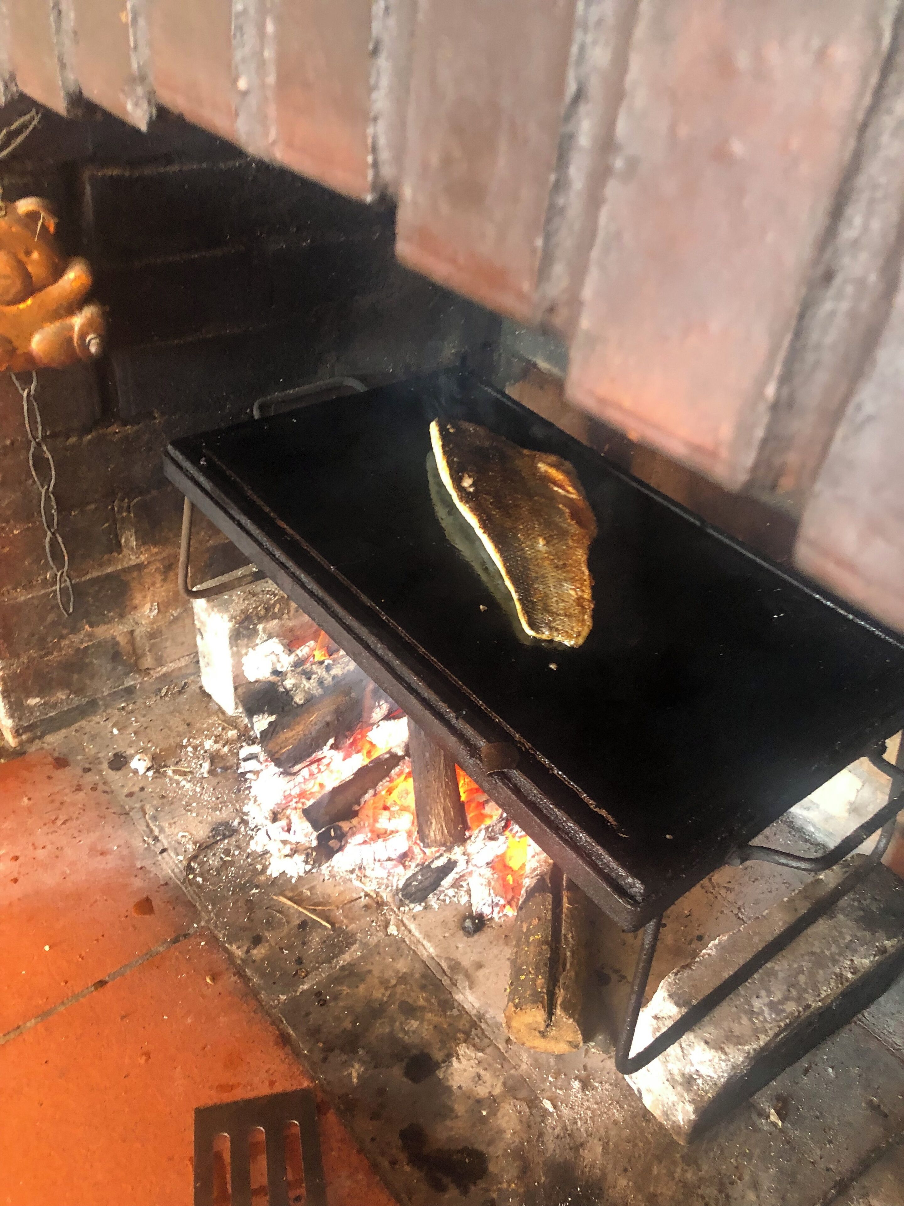 Una torta plana cocinándose en un fogón portátil sobre fuego abierto.