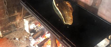 Una torta plana cocinándose en un fogón portátil sobre fuego abierto.