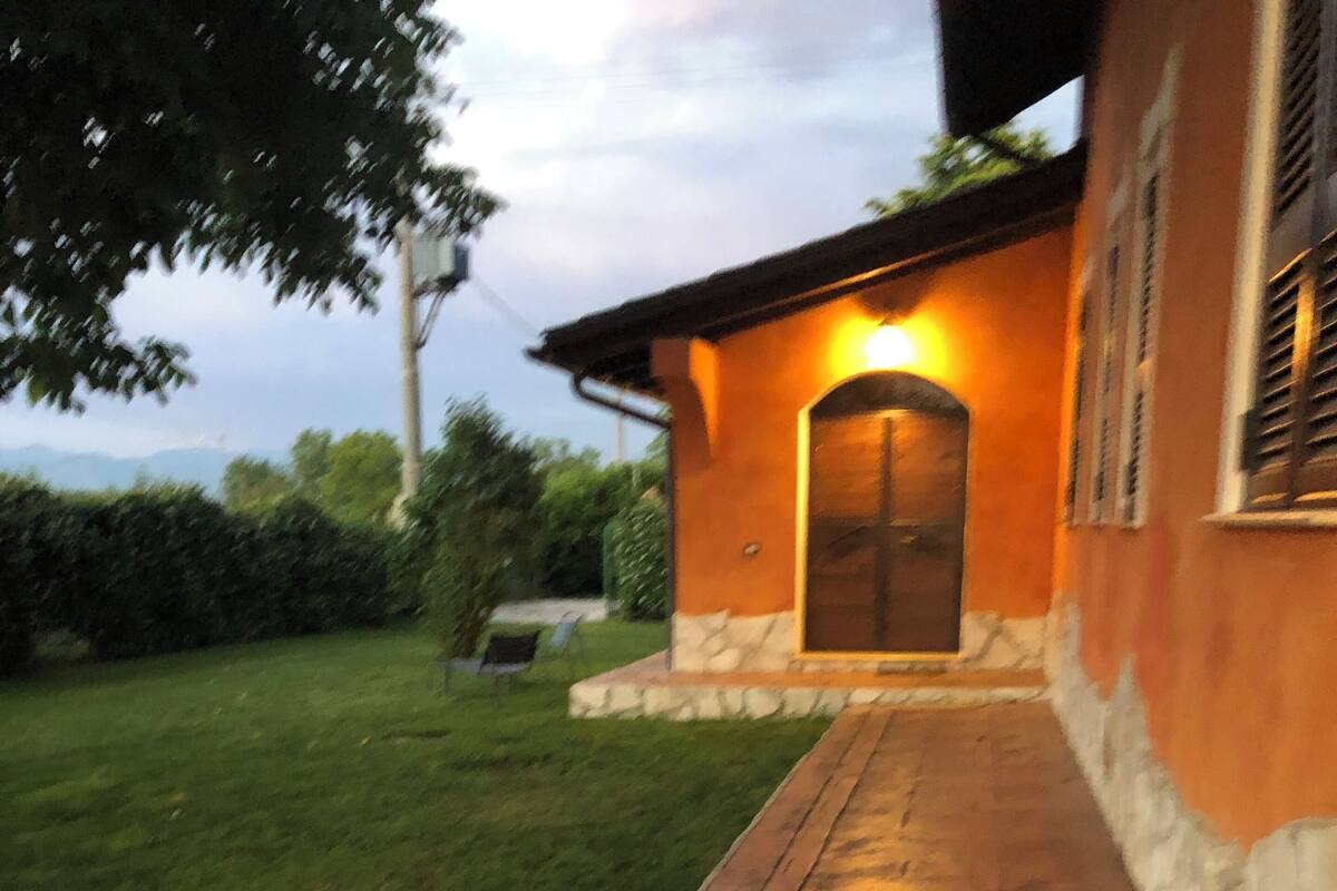 A paved pathway leading to a building with a stone facade and a lit entrance.