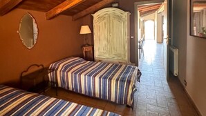 Un dormitorio acogedor en el ático con dos camas, vigas de madera, un espejo y vista al pasillo.
