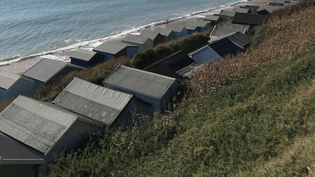 Une vue sur la côte, avec des cabanes de plage et un ciel dégagé.