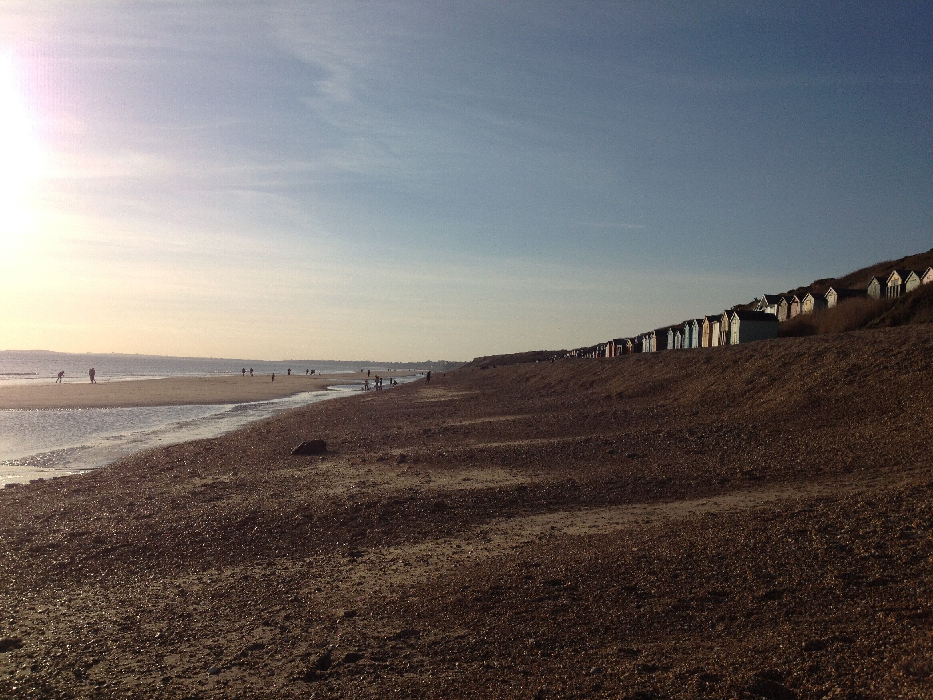 A beach with a row of wooden huts along the shore.