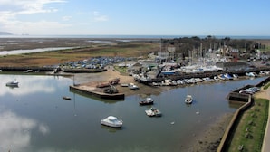 Un port de plaisance avec des bateaux amarrés, une jetée et un bâtiment doté de nombreuses fenêtres.