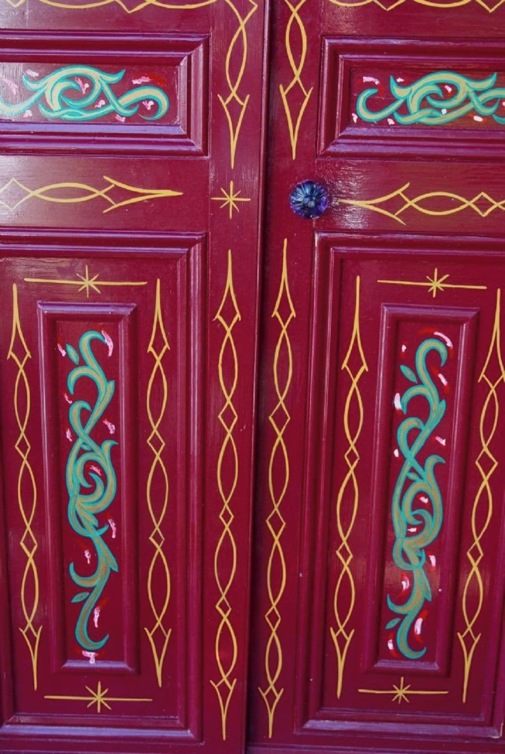 A set of red doors with intricate gold and teal designs.