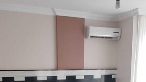A neatly made bed with white linens, a dark headboard, and an air conditioning unit above it. - Aslan Apart Otel (Aydincik)