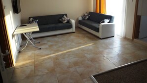 A living room with two sofas, a small table, and a TV mounted on the wall. - Aslan Apart Otel (Aydincik)
