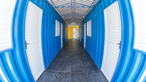 A corridor with blue and white doors, a black floor, and a yellow door at the end. - Residencial Villa Container (Campinas)