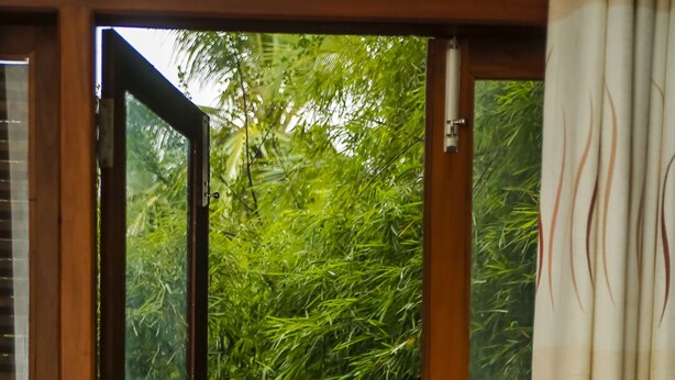 An open wooden door leading to a wooden deck with a view of lush green trees. - Silver Crown Nature Resort (Anuradhapura)