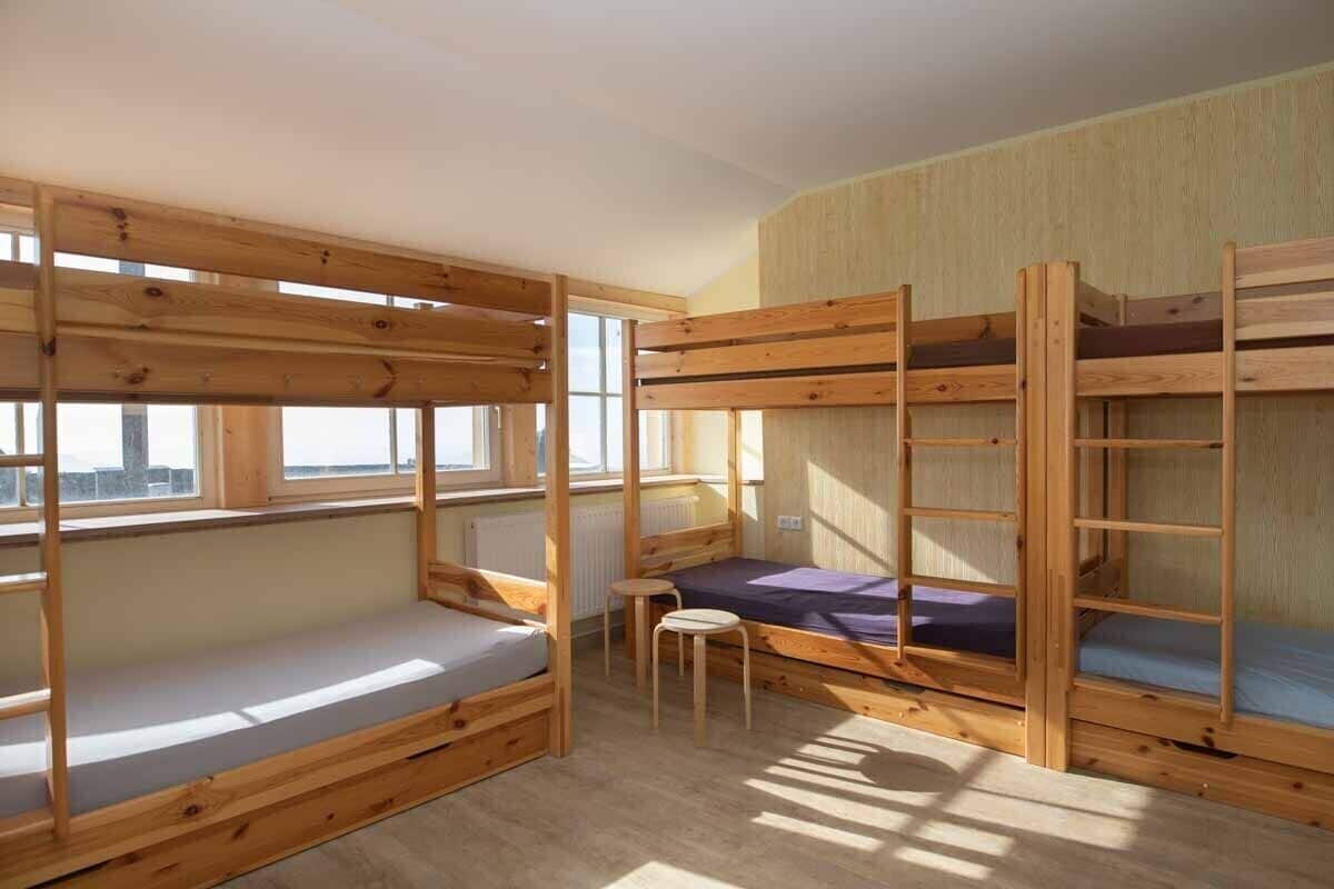 A room with bunk beds, a small table, and a window.