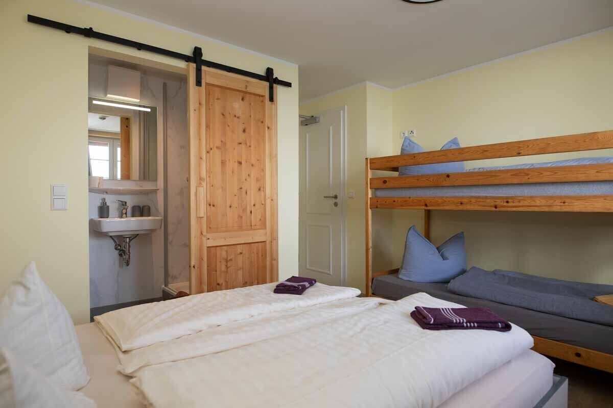 A room with a bunk bed, a small sink, and a sliding door.