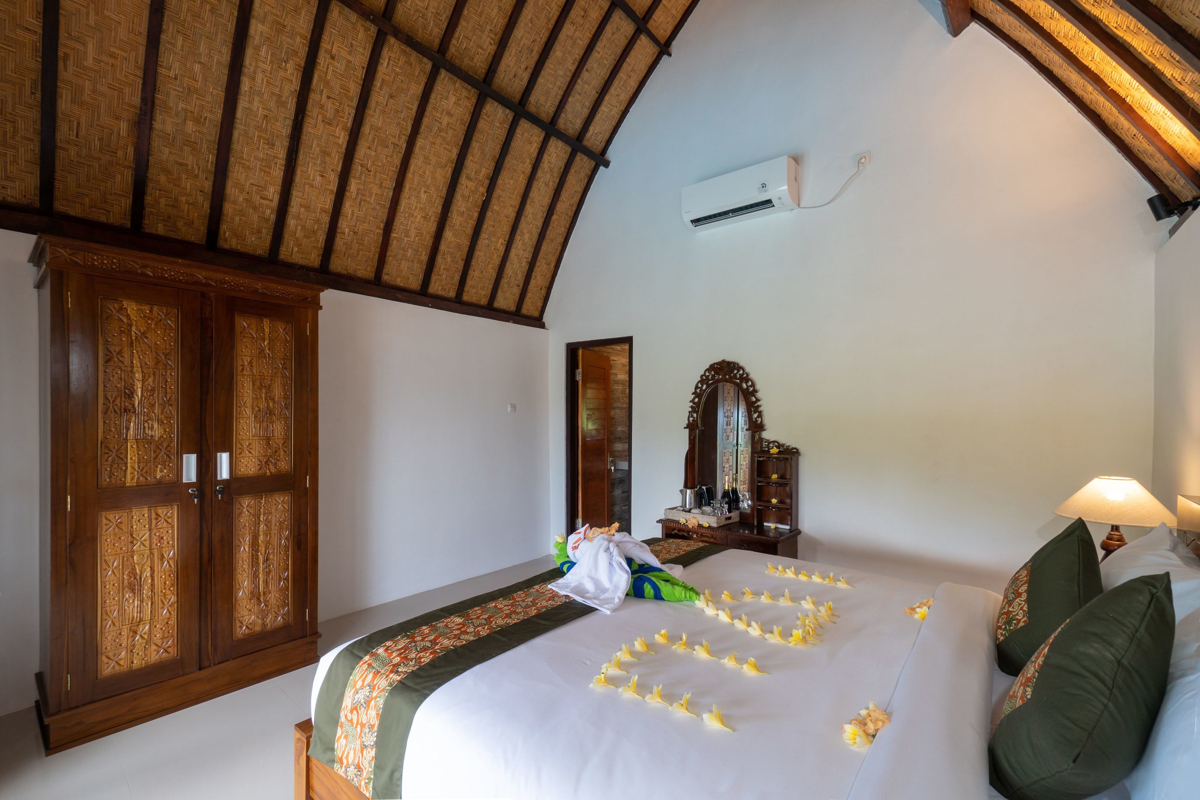 A room with a bed, a wardrobe, a mirror, and an air conditioning unit.