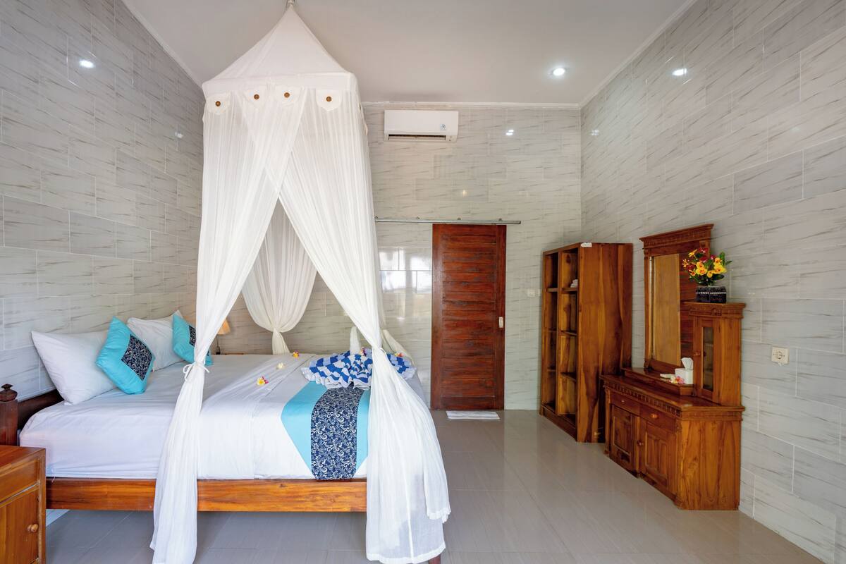 Une chambre à coucher avec un lit à baldaquin, une armoire en bois, un miroir et une porte.