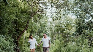 Una pareja caminando por un sendero de tierra rodeado de abundante vegetación.