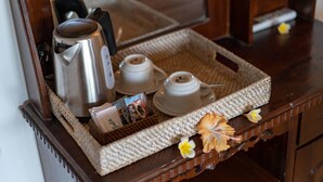 Una bandeja con una cafetera, dos tazas y un sobre de café sobre una mesa de madera.