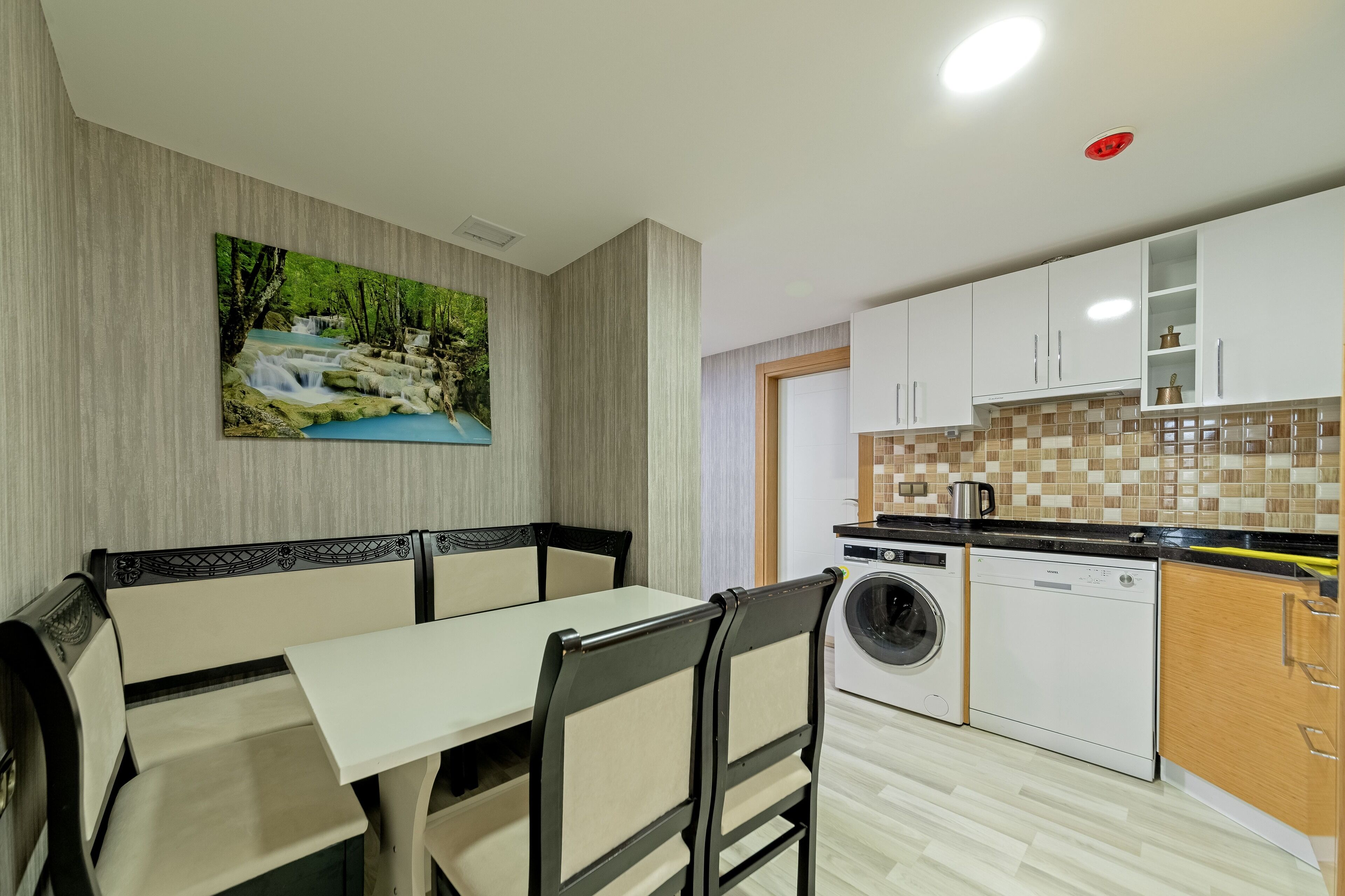 A modern kitchen with white cabinets, a tiled backsplash, and a built-in washing machine.