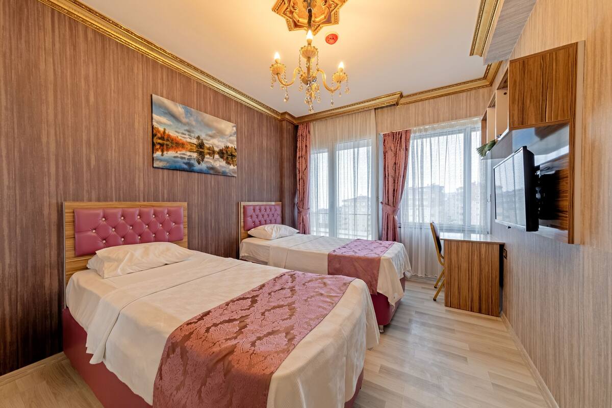 Una habitación de hotel con dos camas, televisión y escritorio.