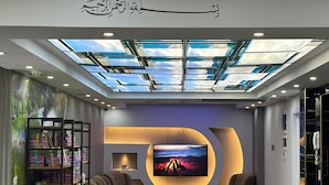 Uma sala de estar moderna com uma televisão de tela grande, assentos confortáveis, estante e teto skylight.