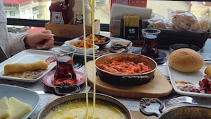 Uma mesa de jantar com diversos pratos, um sinal com menu por QR code e vista para o mar e edifícios.